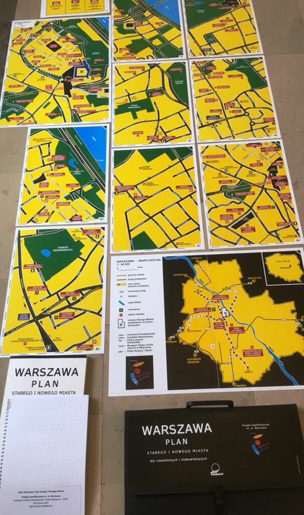 Arkusze map tyflologicznych Planu Warszawy rozłożone na podłodze.
