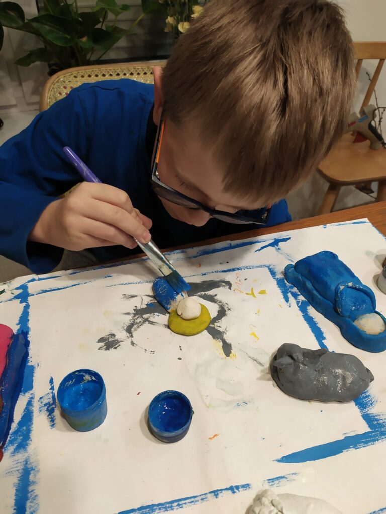 Ignacy maluje farbami figurki wykonane z masy solnej.
