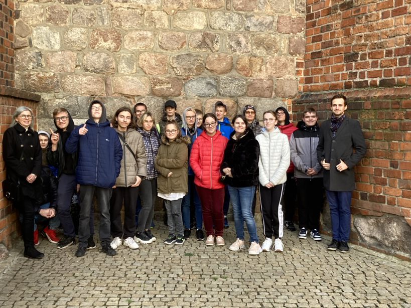Wspólne zdjęcie uczestników wycieczki przed fragmentem romańskiego muru Katedry