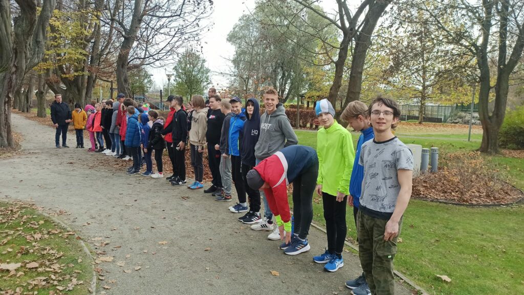 Grupa uczniów na chwilę przed startem w biegu przed wejściem do alejek. 