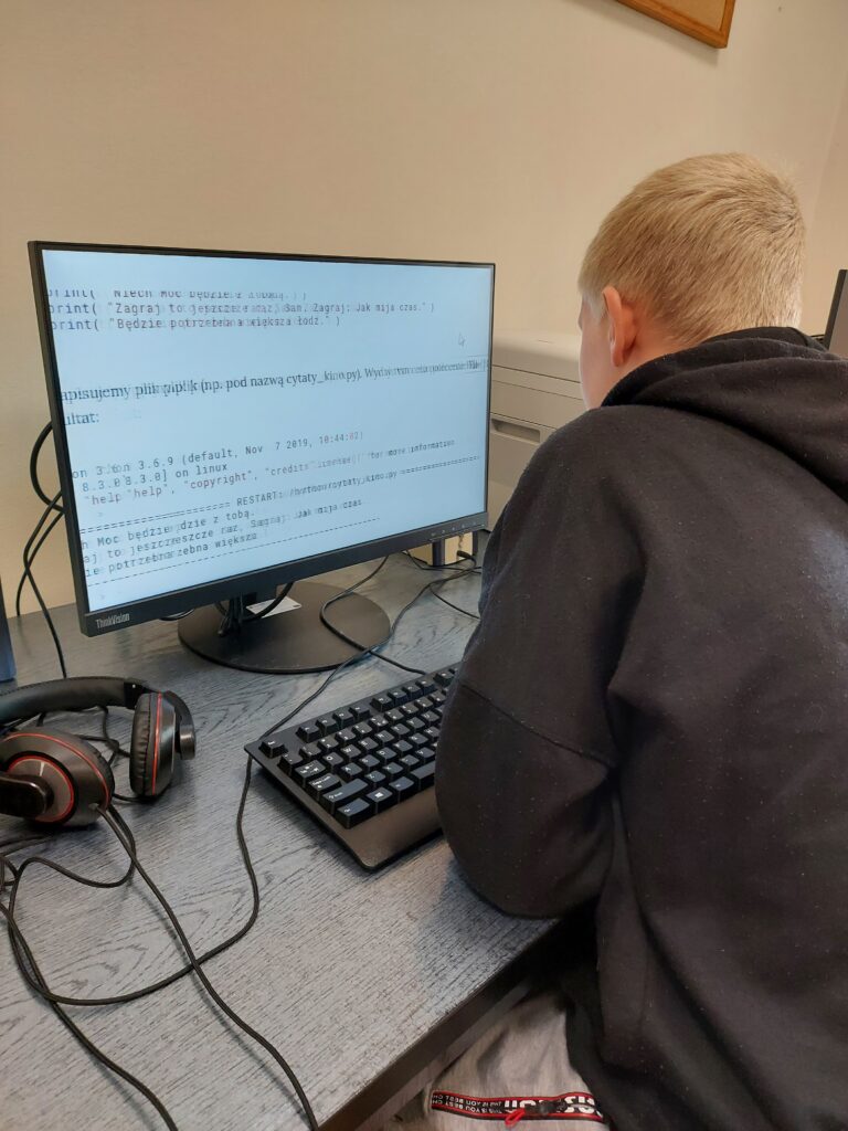 Uczeń siedzą przy komputerze podczas zajęć z informatyki
