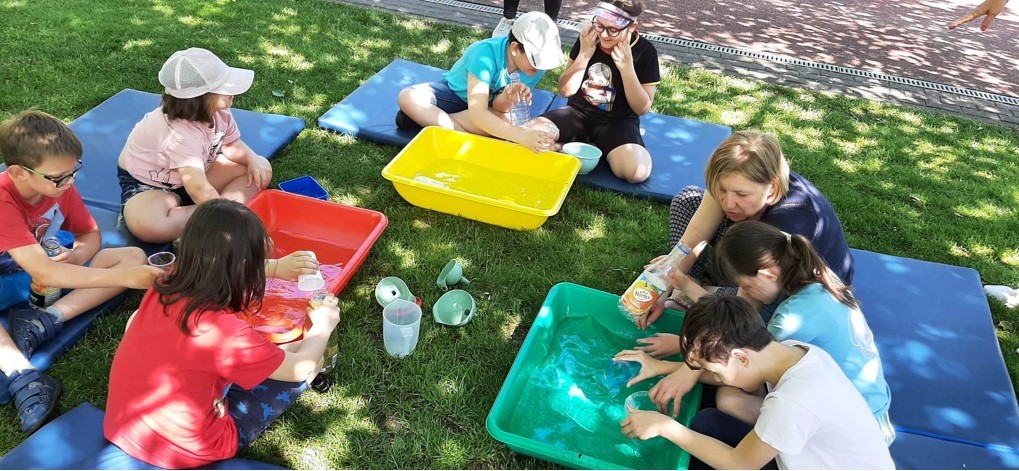 Grupa dzieci bawi się wodą, sprawdzamy pojemności różnych naczyń.