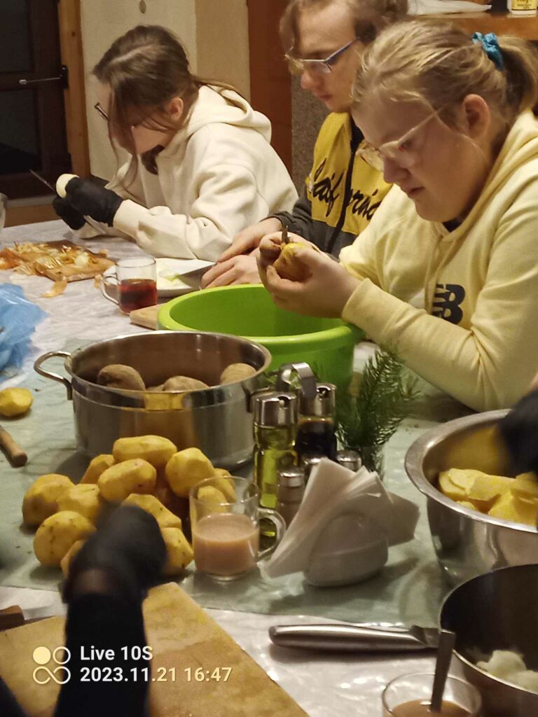 Julia M., Kuba i Julia L. obierają przy jednym stole ziemniaki podczas warsztatów kulinarnych.