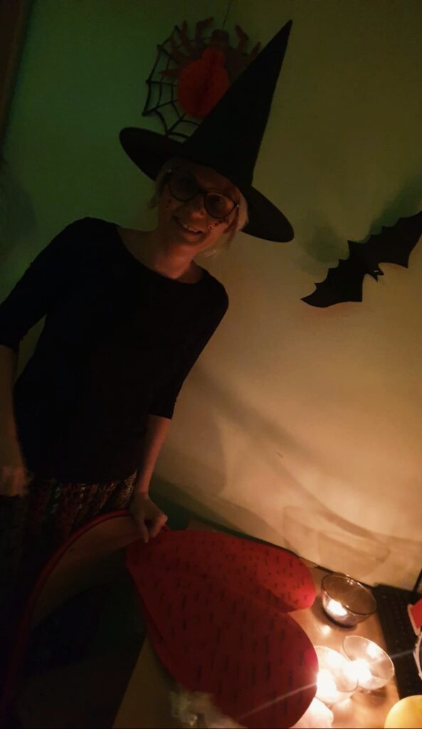 Pani Monika w kapeluszy czarownicy, uśmiecha się. Na stole leży duże serce z imionami