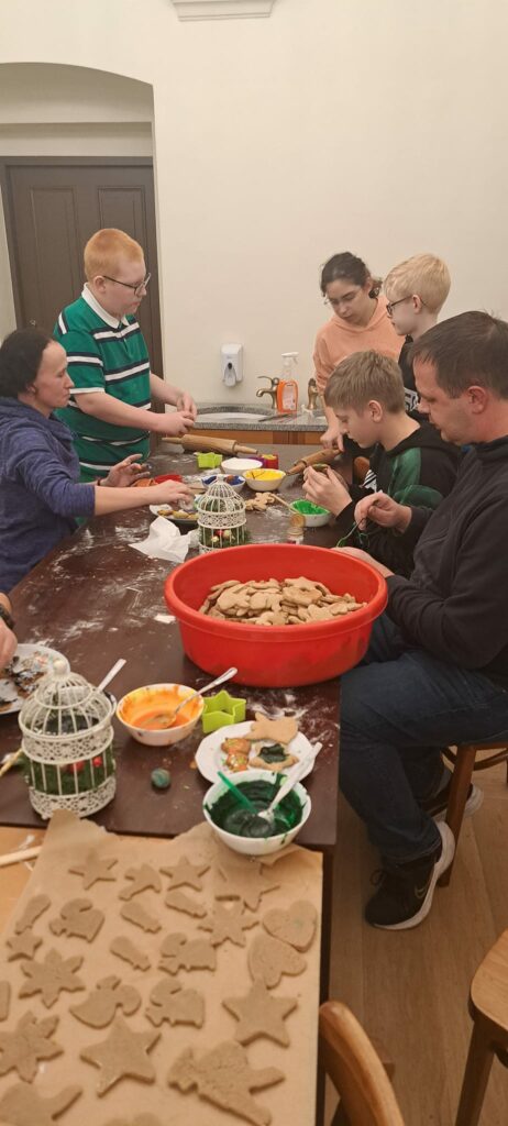 Mała stołówka. Chłopacy wraz z wychowawcami siedzą przy stole. Rozwałkowują ciasto i wykrawają foremkami kształty.