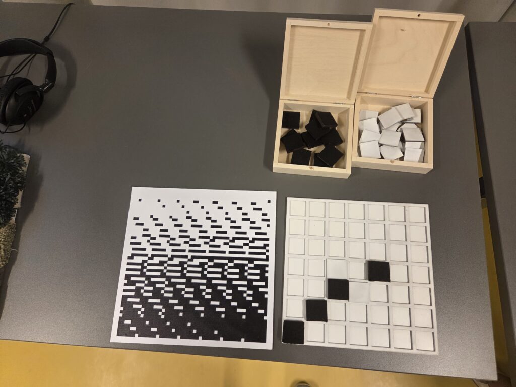 układanka z polami wklęsłymi i kwadratowe puzzle białe oraz czarne do układania obrazów na niej.